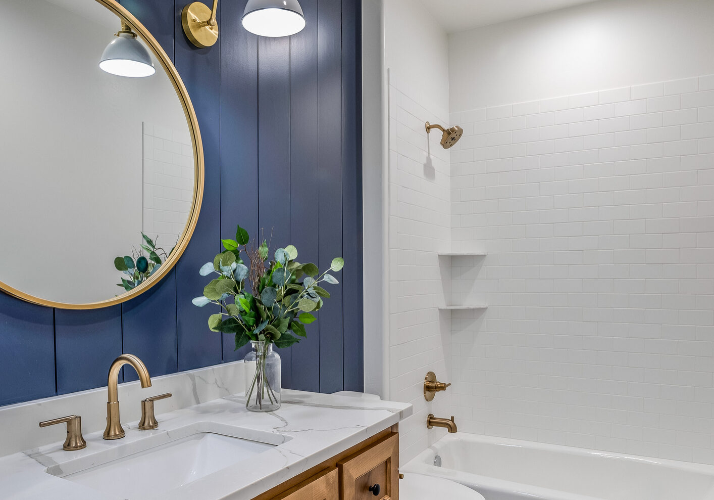 Blue shiplap walls with round mirror and sconce lights